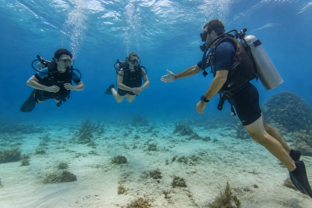 Instructor supervising two beginner scuba divers near Cancun