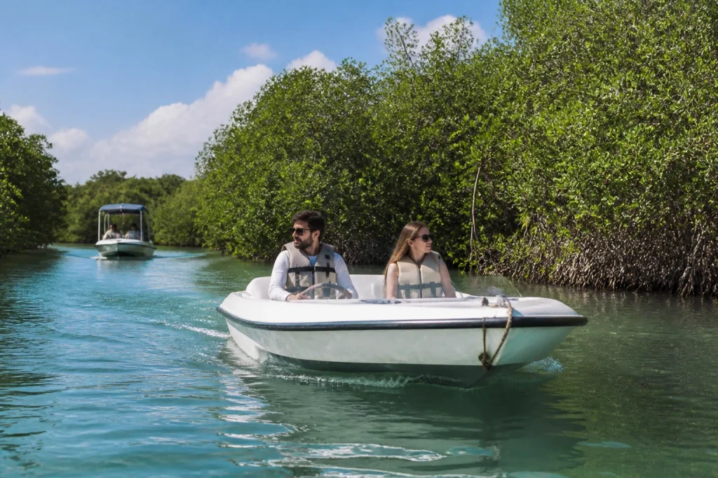 Travelers driving a small speedboat through Cancun mangroves
