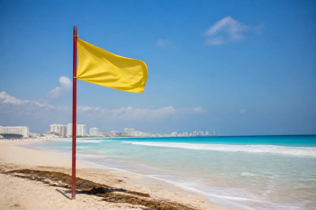 Yellow beach safety flag near the sea in Cancun