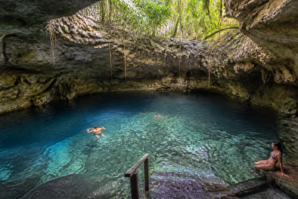 Natural limestone cenote surrounded by tropical vegetation