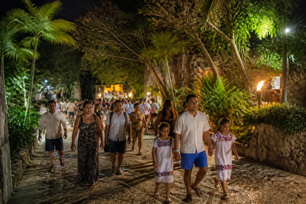 Visitors leaving a tropical park after an evening performance